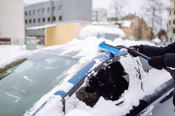 istock Portrait of smiling man cleaning snow off his car during winter snowfall. 1448563473