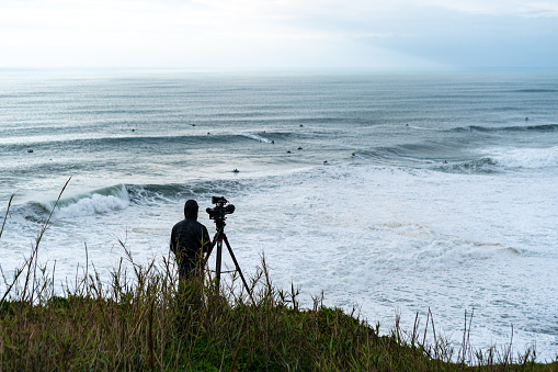 Rear view of videographer filming surfers in Nazare Surfing Challenge