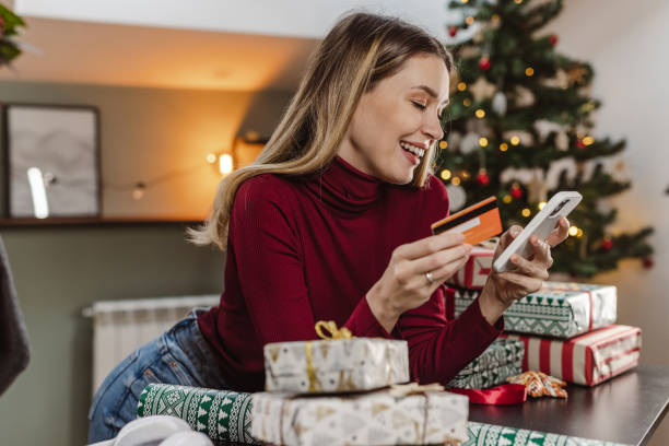 istock Beautiful young woman using a credit card and smart phone for e-commerce during Christmas time 1448570813