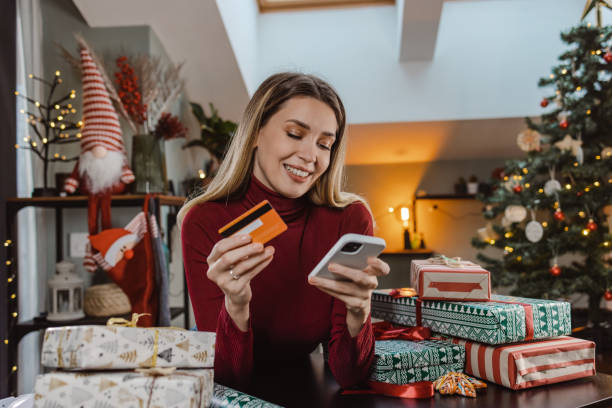istock Beautiful young woman using a credit card and smart phone for e-commerce during Christmas time 1448572374