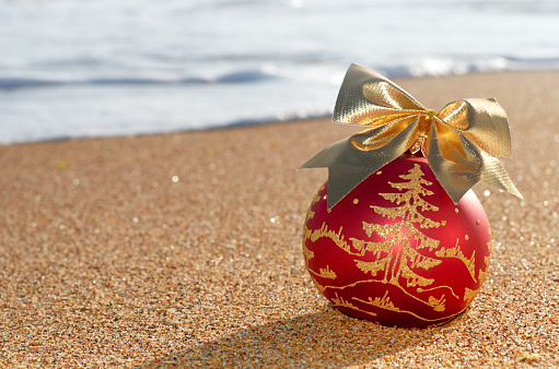 Christmas tree decoration on the beach sand against the background of sea wave foam