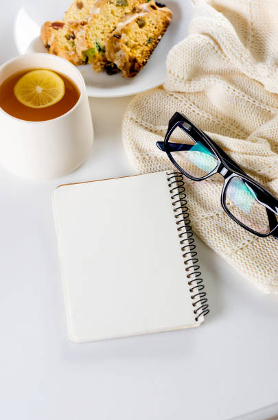 istock Cup of lemon tea, Christmas fruitcake, eyeglasses and empty notebook. 1448576206