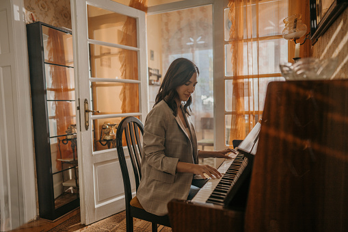 Beautiful young woman playing piano in her beautiful home.