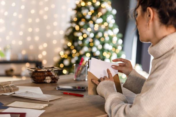 Young woman putting the Christmas letter she wrote in an envelope stock photo