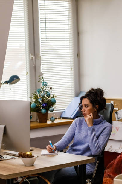istock Young woman brainstorming ideas while working at her desk at the office during Christmas holidays 1448584116