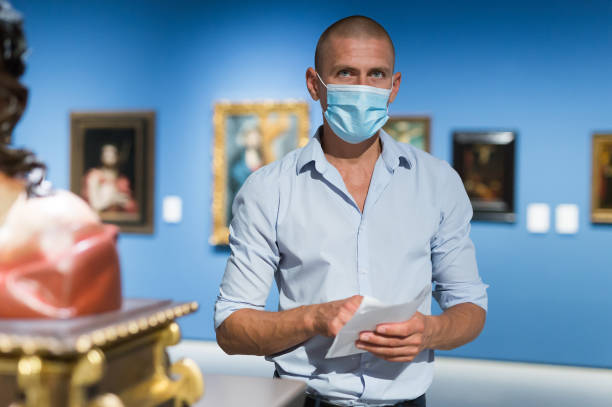 istock Man in mask standing in picture gallery 1448584971