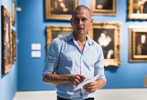 Portrait of European adult man standing in gallery and watching exposition