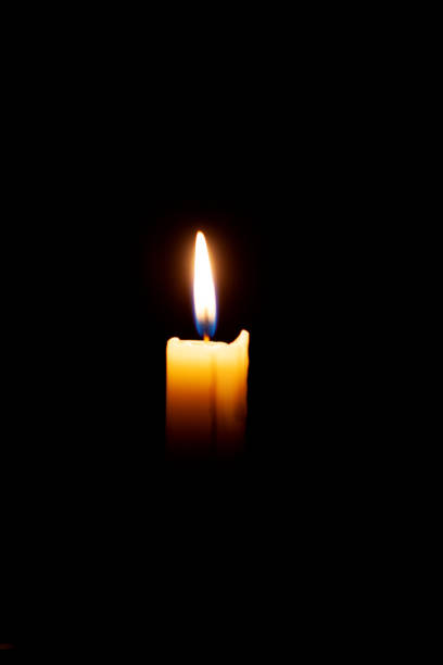 istock A burning candle on a black background in a dark room. 1448586215