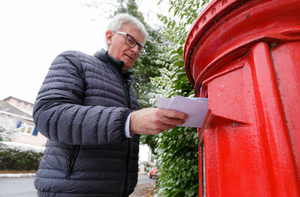 istock Senior man posting a letter in traditional red British mailbox 1448588162