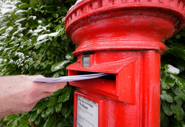 istock Senior man posting a letter in traditional red British mailbox 1448588163