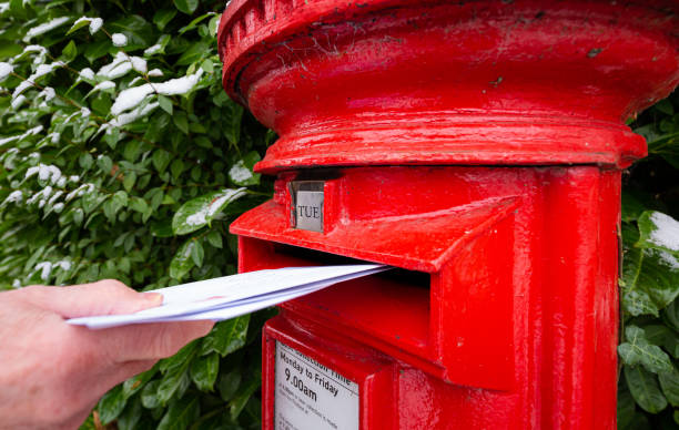 istock Senior man posting a letter in traditional red British mailbox 1448588236