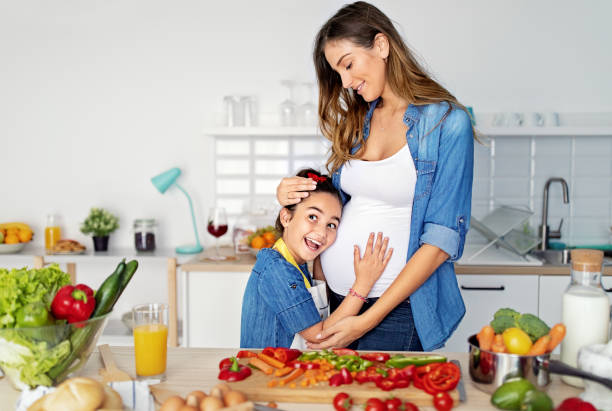 istock Pregnant mother and daughter cooking in a kitchen 1448588432