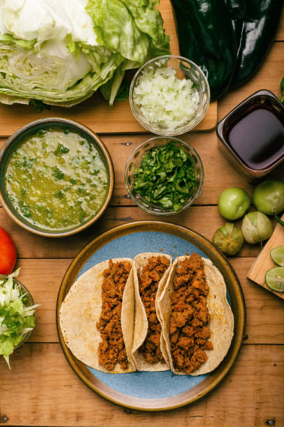 istock Marinated beef tacos, bowl with salsa verde and vegetables on a wooden table. Tacos de adobada. 1448589730
