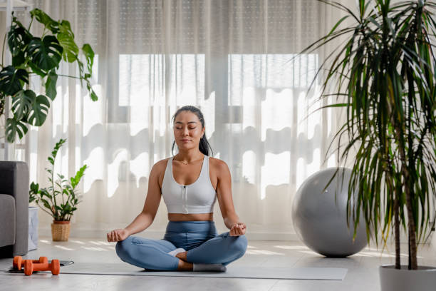 istock Young Asian woman meditating by doing yoga exercise 1448591672