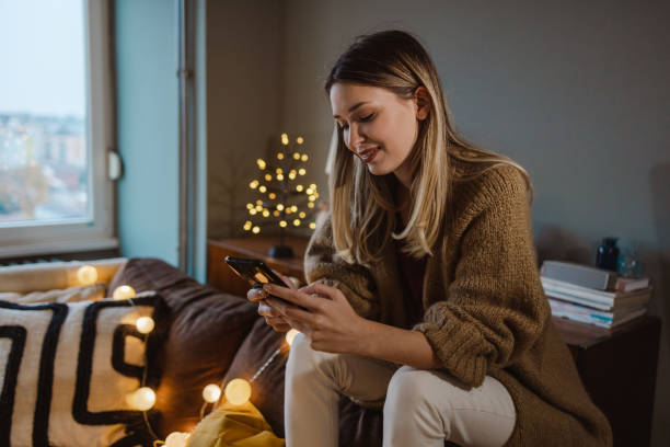 istock Young smiling woman using smart phone during Christmas time 1448591739