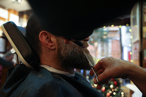 Man getting his beard trimmed in barber shop