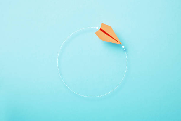 istock Orange Paper Plane Moving On Circular Trajectory On Blue Background 1448592611