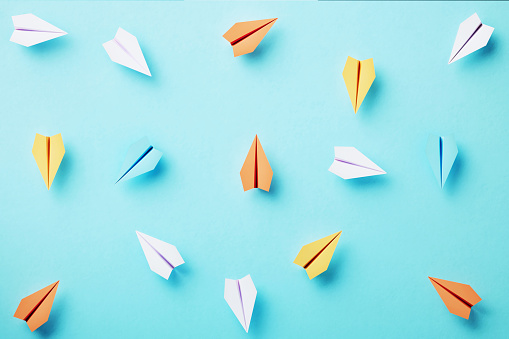 Different colored paper planes on blue background, Diversity concept.