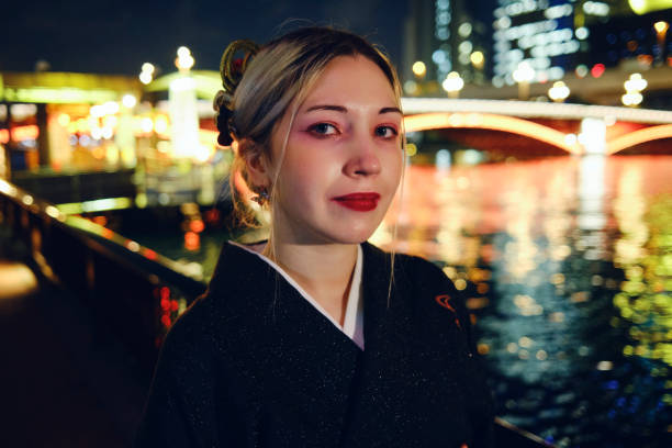 A young European woman wearing a Kimono exploring the Asakusa area of Tokyo Japan at night.