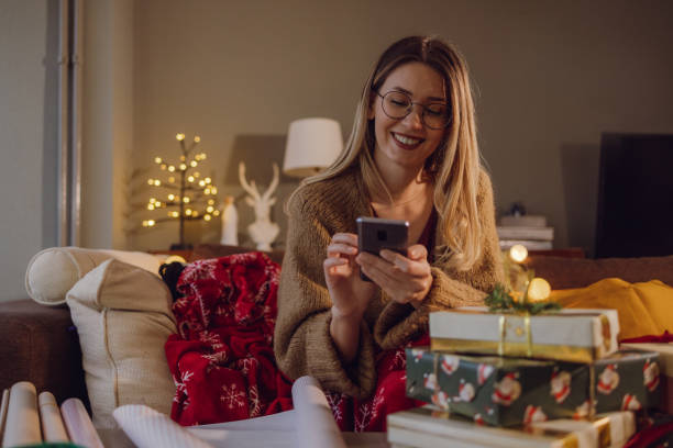 istock Lovely woman using smart phone during Christmas time at home 1448593130
