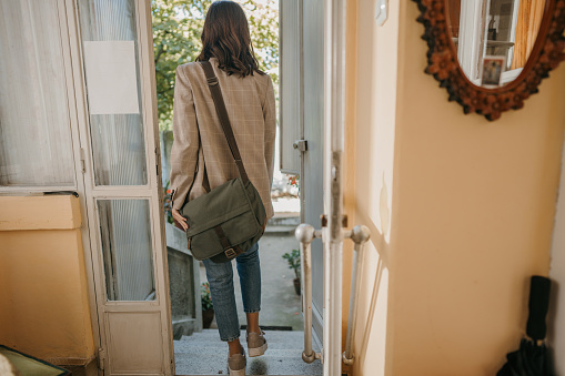 Unrecognizable young woman is leaving her home.