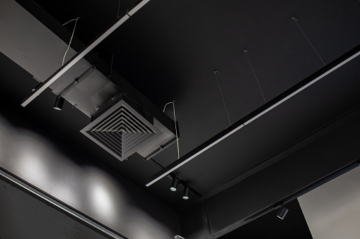 Supply and exhaust ventilation pipe on the ceiling of a retail space or warehouse or other commercial real estate object. Ceiling, lighting and communications in black. Copy Space