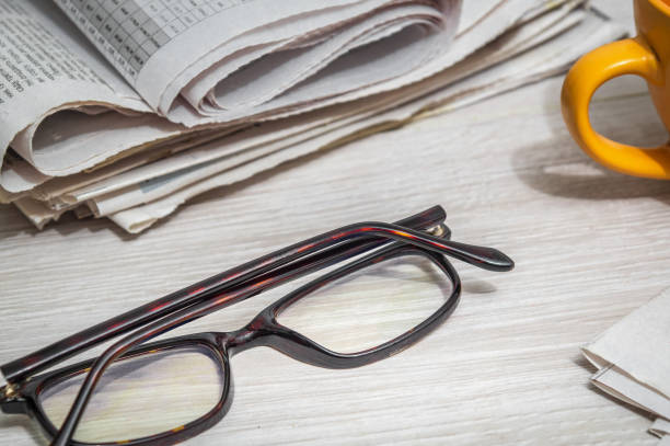 istock Glasses for reading newspapers on the desk and a mug. Home environment during planning and analysis 1448596172
