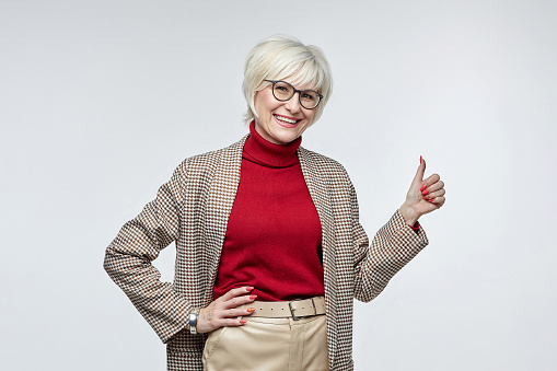 beautiful elderly woman with glasses gives a thumbs up. the concept of a business woman leader.