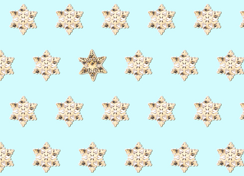 Geometric Christmas pattern made of wooden toy snowflakes on a pastel blue background. Winter concept. Flat lay.