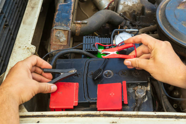 istock Close up of driver hands charging old car battery using electricity through jumper cables. Repair of an old car 1448597113