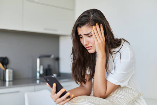 istock Sad young man with depression crying using his mobile phone at home 1448597188