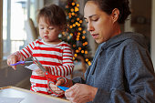 Mom and toddler daughter cutting paper snowflakes