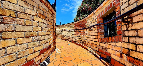 A red brick pathway curving round out of sight under a blue sky