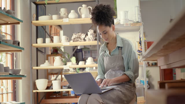 Business woman, laptop and small business owner in pottery design working for startup at the store. African American female entrepreneur drinking coffee while typing on computer for online marketing