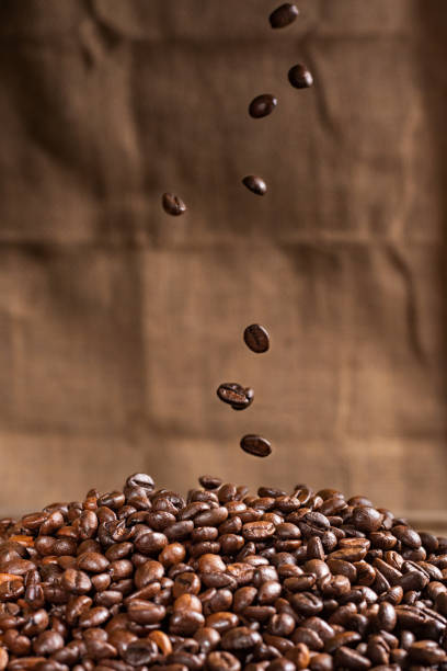 granos de café cayendo sobre una montaña de granos de café tostados, de cerca. - selective focus coffee coffee crop cafe fotografías e imágenes de stock