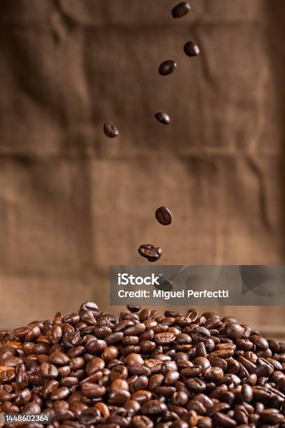 Coffee Beans Falling On A Mountain Of Roasted Coffee Beans Closeup Stock Photo - Download Image Now
