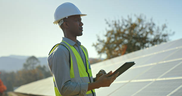 istock Solar energy, tablet or black man on rooftop for solar panels grid inspection or development in summer. Designer, engineering or African manager checks safety maintenance of photovoltaic construction 1448604940