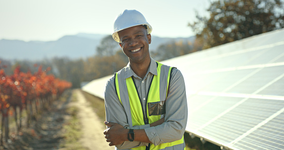 Portrait, solar energy or engineering manager by solar panels roof in a nature farm smiles with pride for success. Innovation, construction or black man working on sustainability development project