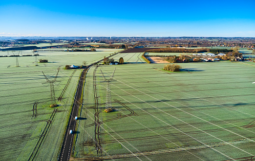 Aerial view of agricultural landscape with cables. Country road crossing through