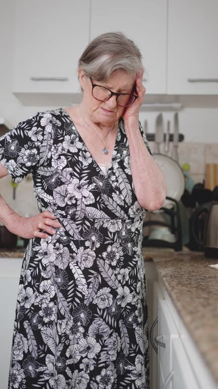 Senior woman suffering back pain while cleaning the kitchen bench