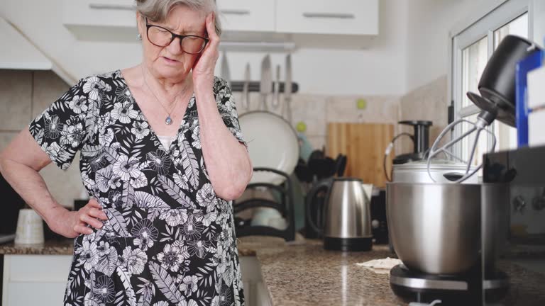 Gray hair old woman suffering back pain while cleaning the kitchen