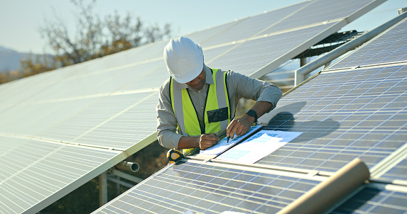 Construction worker, planning and solar panel innovation and safety inspection. Electrician, solar energy maintenance and employee working on strategy documents or blueprints for renewable energy