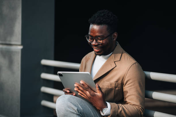 istock Handsome young black man using digital tablet outdoors 1448608322