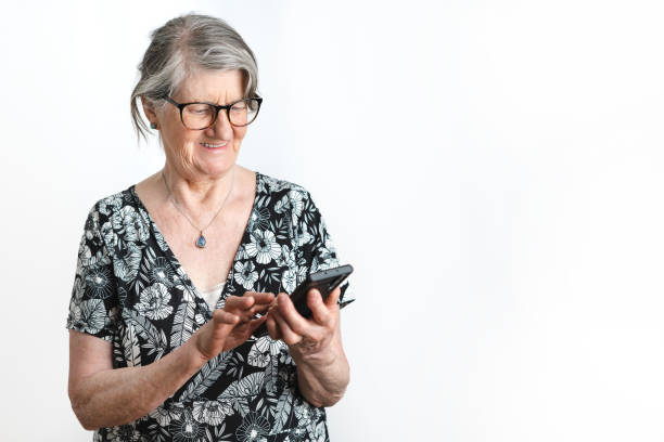 istock Portrait of senior woman smiling while looking at smart phone over isolate white background studio shot 1448610539