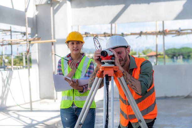 istock Construction Worker Using Theodolite Surveying Optical Instrument for Measuring Angles in Horizontal and Vertical Planes on Construction Site. Engineer and Architect Using Tablet Next to Surveyor. 1448611620