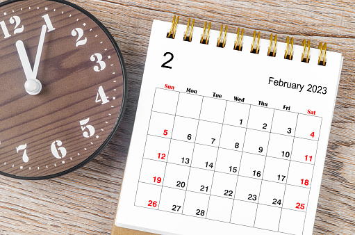 February 2023 Monthly desk calendar for 2023 year with wooden clock.