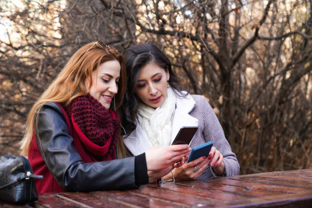 istock two happy young women outdoors looking at cell phone 1448618442