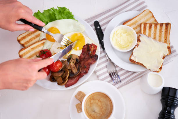 istock Fried eggs, bacon, tomato, toasted bread in white ceramic plate and cup of coffee 1448618574
