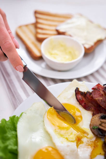 istock Fried eggs, bacon, tomato, toasted bread in white ceramic plate and cup of coffee 1448618580
