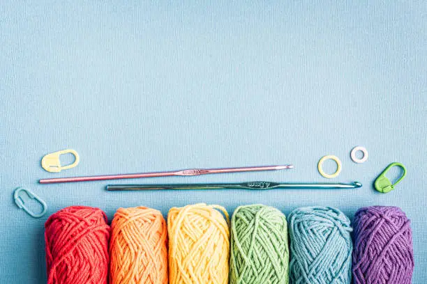 Photo of Crochet composition with cotton rainbow yarn, crochet hooks and accessories. Flat lay overhead shot with copy space, toned photo